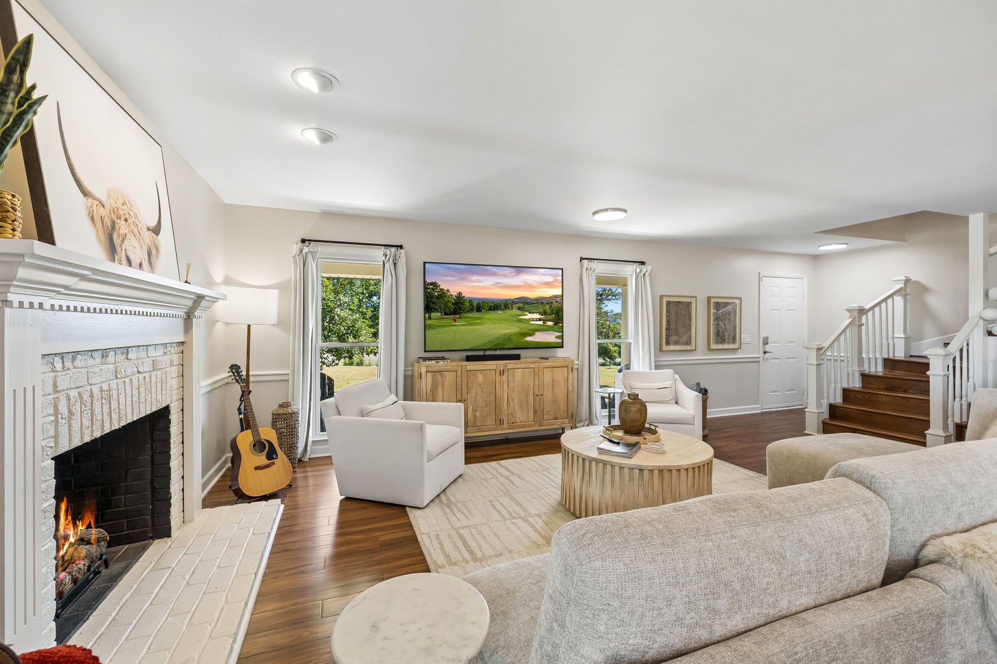Amplia sala de estar con chimenea, televisor y vista a un campo de golf.