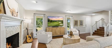 Amplia sala de estar con chimenea, televisor y vista a un campo de golf.