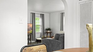 Un comedor con una mesa de madera, una silla tapizada de gris y un cuadro en la pared.