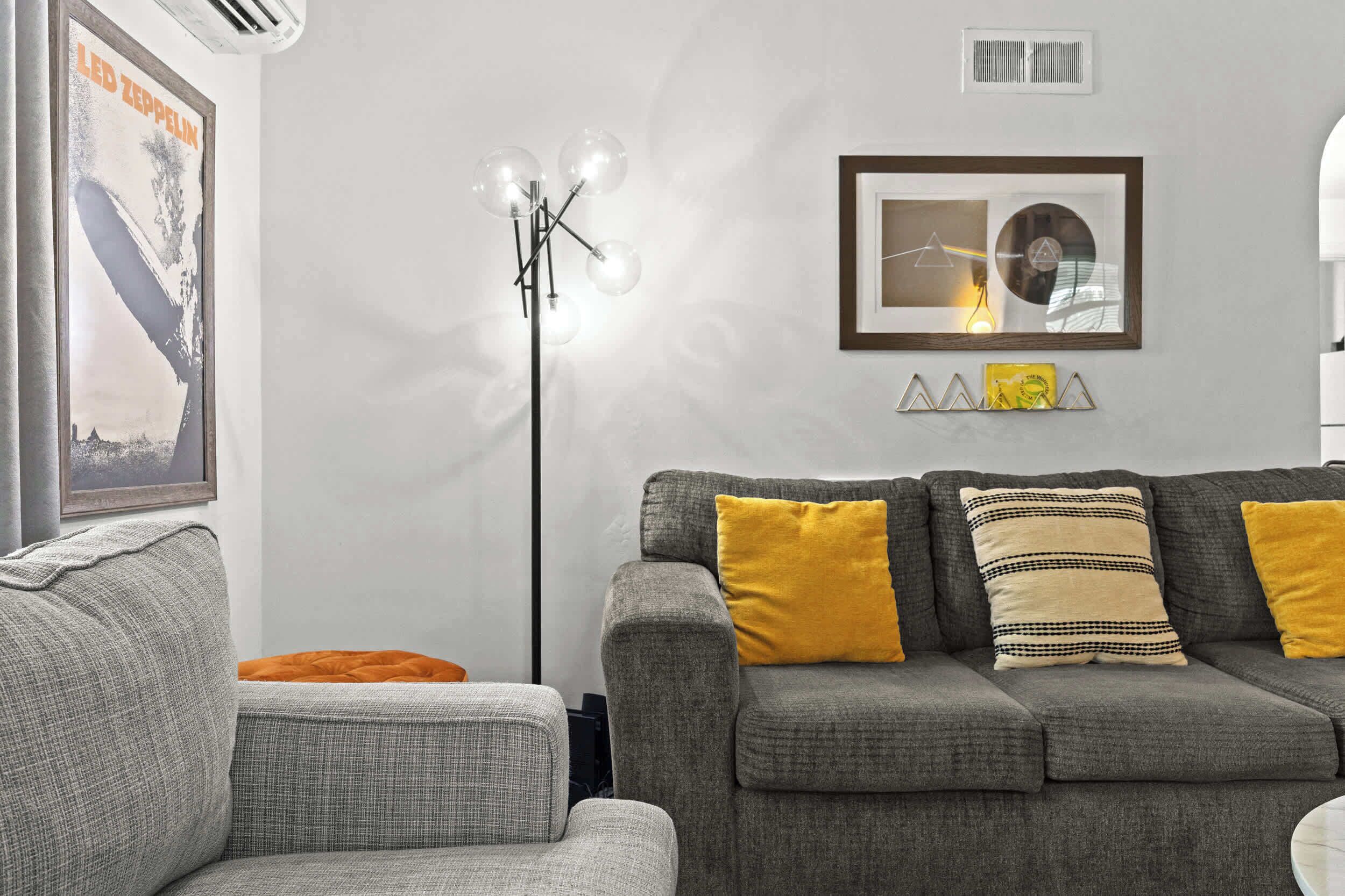 A living room with a grey sofa, a floor lamp, and a framed picture on the wall.