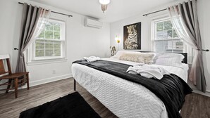 Un dormitorio con cama, ventilador de techo y ventana con cortinas.