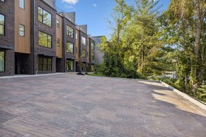 Sisäpiha, jossa on tiililaatoitettu lattia. Sitä ympäröivät modernit rakennukset, joissa on suuret ikkunat, ja sen läpi kulkee puurivistöinen kävelytie.