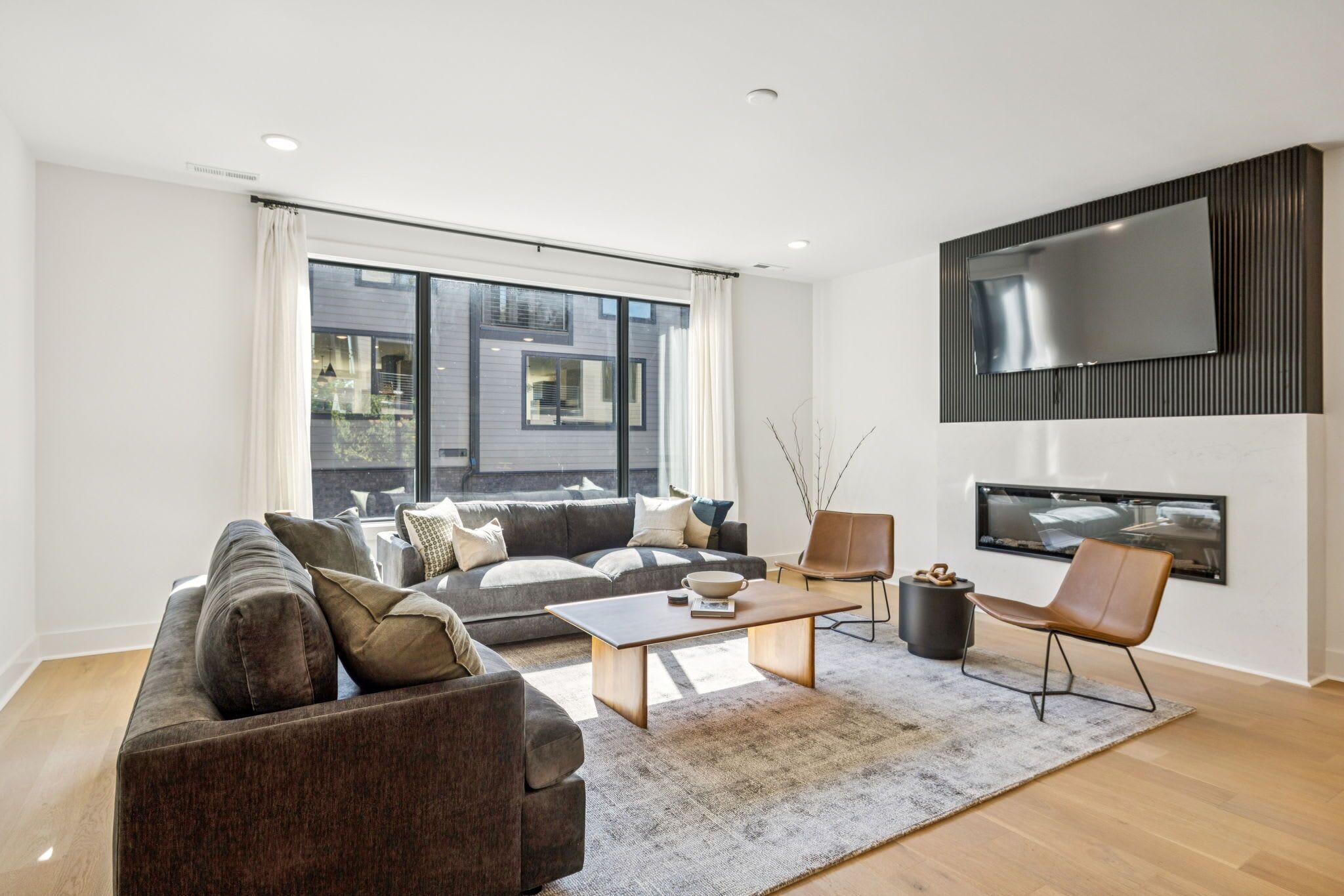 A modern living room with a sofa, coffee table, and a flat-screen TV mounted on the wall.