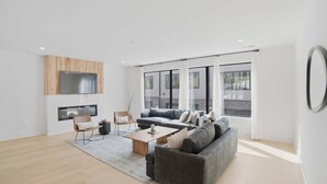 A modern living room with a grey sofa, wooden coffee table, and a TV mounted on a wooden panel. - Luxury retreat with exclusive rooftop hot tub (Nashville)