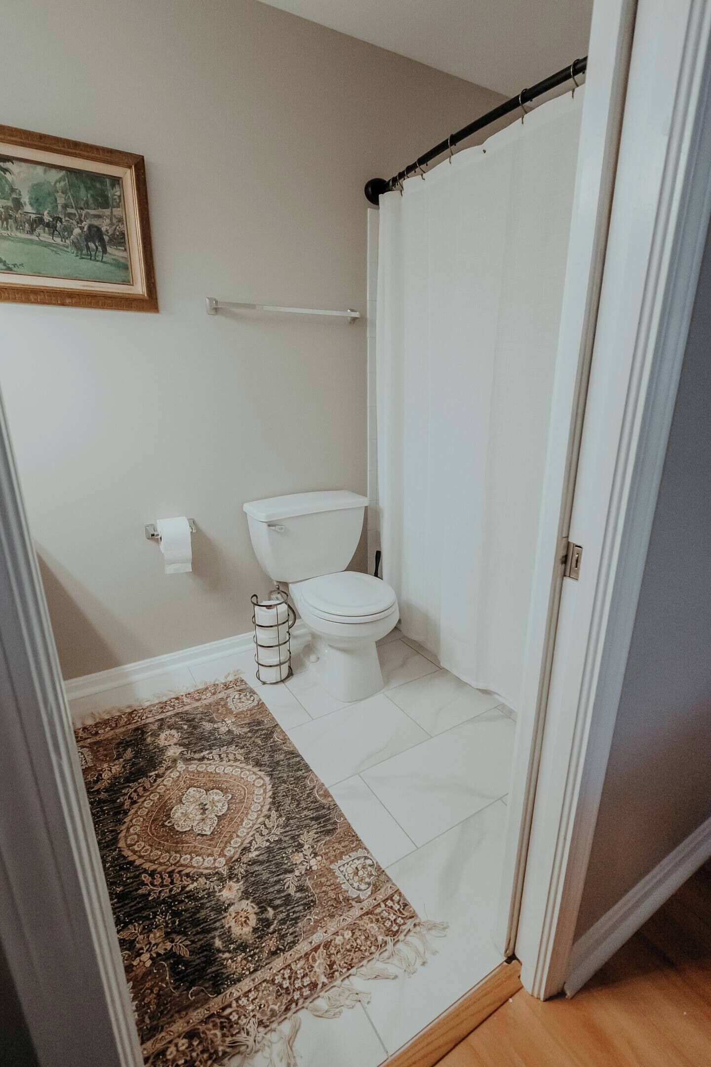 Ein Badezimmer mit Toilette, Toilettenpapier, einer Duschvorhang und einem gemusterten Teppich.