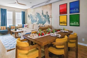 A dining area with a wooden table set for four, surrounded by yellow chairs.