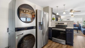 A modern kitchen with stainless steel appliances, a built-in washer, and a dining area with a ceiling fan. - Spacious family-friendly home w/ exclusive arcade! (New Albany)