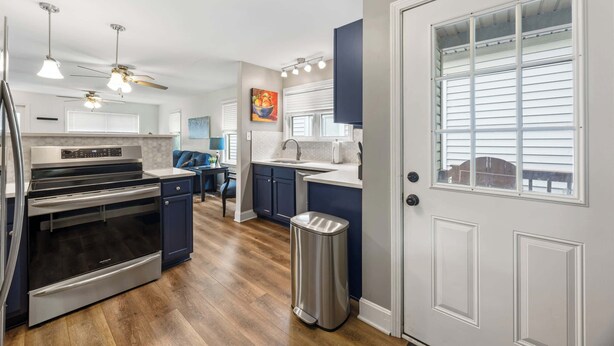 A modern kitchen with stainless steel appliances, a dining area, and a view of the outside through a window with blinds. - Spacious family-friendly home w/ exclusive arcade! (New Albany)