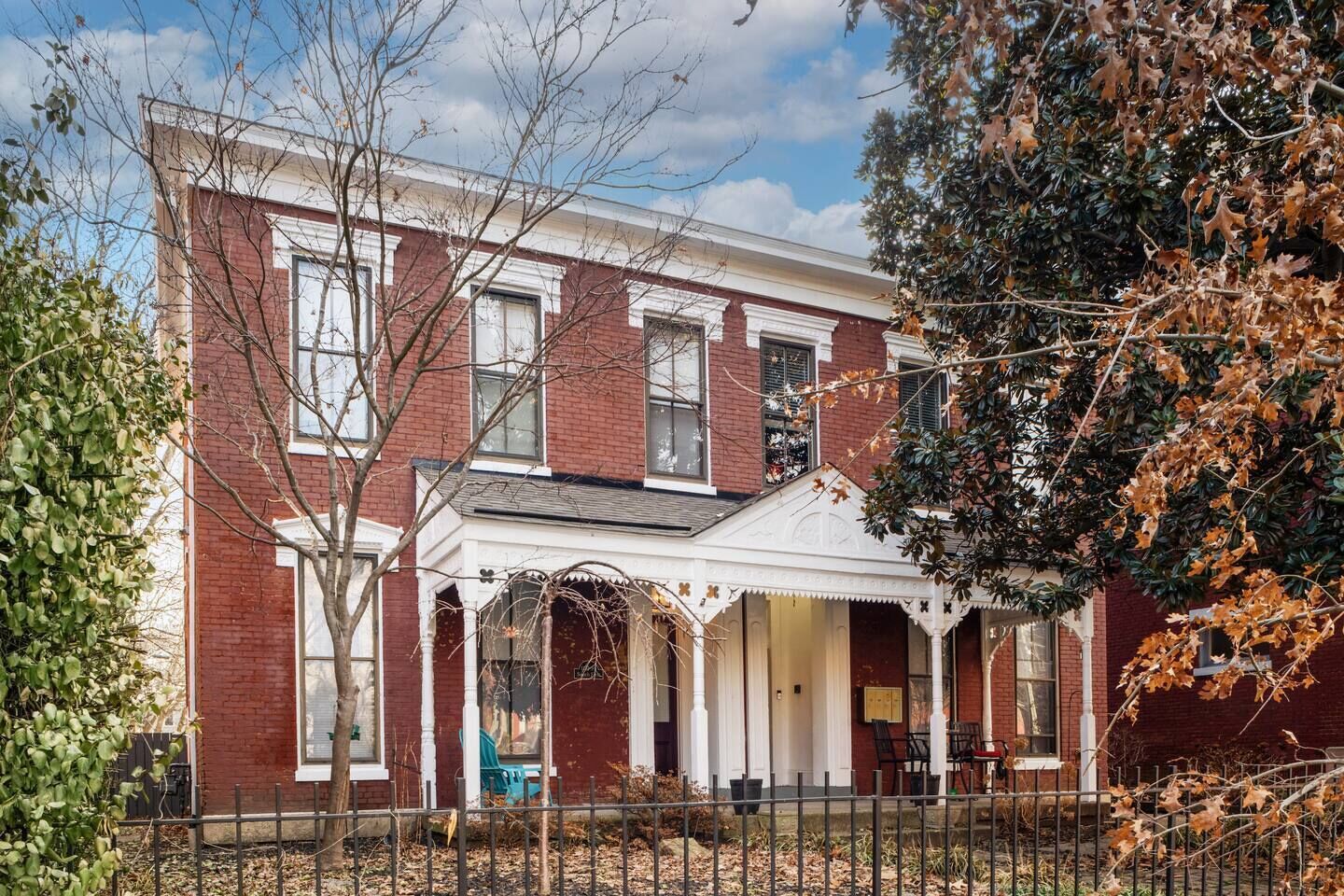 A two-story brick house with a porch and a small front yard.