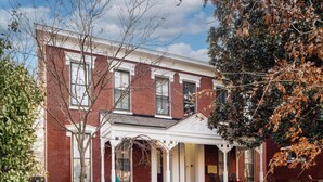 A two-story brick house with a porch and a small front yard. - Modern apartment near Nulu and other attractions! (Louisville)