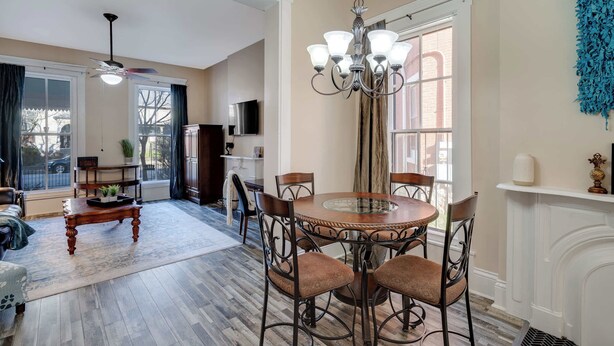 A dining area with a round table and chairs, a chandelier, and a fireplace. - Modern apartment near Nulu and other attractions! (Louisville)