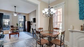 A dining area with a round table and chairs, a chandelier, and a fireplace.
