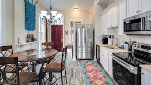 A modern kitchen with white cabinets, stainless steel appliances, a dining table with chairs, and a decorative rug. - Modern apartment near Nulu and other attractions! (Louisville)