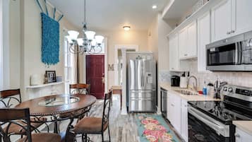A modern kitchen with white cabinets, stainless steel appliances, a dining table with chairs, and a decorative rug.