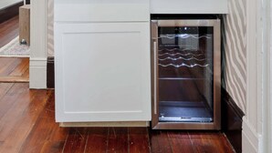 Un baño moderno con lavavajillas integrado, cafetera y espejo con marco dorado.