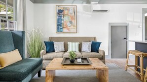 A modern living room with a sofa, coffee table, and a painting on the wall. - Cozy + Spacious 2bd King Suites w. Gym & Parking! (Charleston)