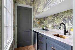 Eine Küche mit einer dunklen Tür, einem Spülbecken und einer Spritzschutzwand mit geometrischem Muster.