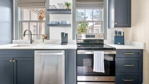 Una cocina moderna con armarios oscuros, un lavavajillas de acero inoxidable, un horno doble y una estufa empotrada.