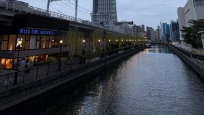 A view of the Tokyo Tower with a river in the foreground and a building labeled "Wise Owl Hostels" to the left. - 3-101: Newly built Apt, 2 min sta., Near Skytree & Asakusa (Sumida City)