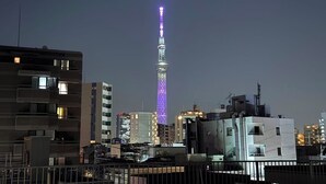 A cityscape at night with a prominent tower lit in purple. - 3-101: Newly built Apt, 2 min sta., Near Skytree & Asakusa (Sumida City)