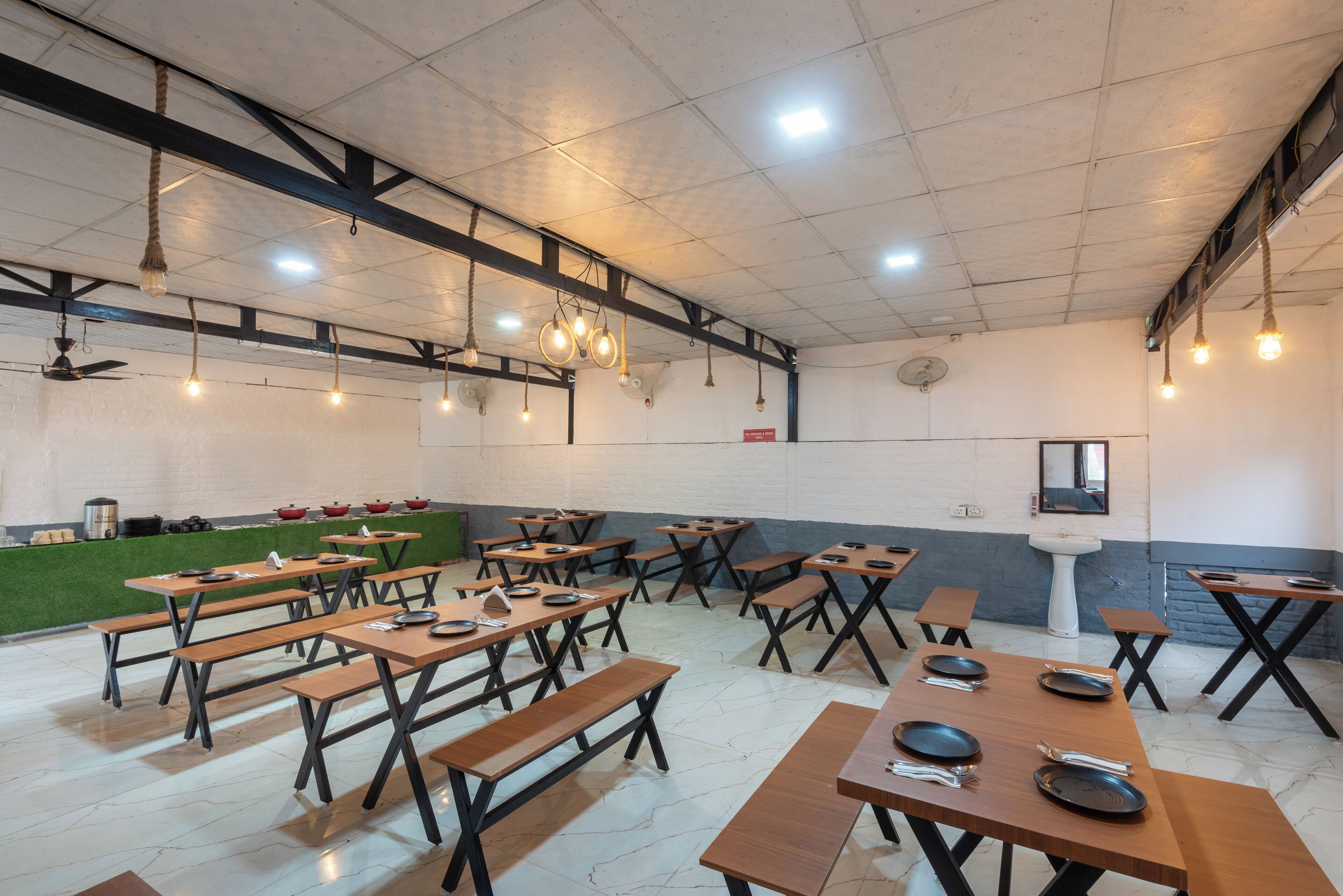 A spacious dining area with wooden tables and benches, ceiling fans, and pendant lighting.