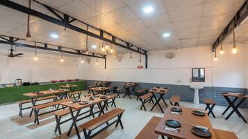 A spacious dining area with wooden tables and benches, ceiling fans, and pendant lighting.