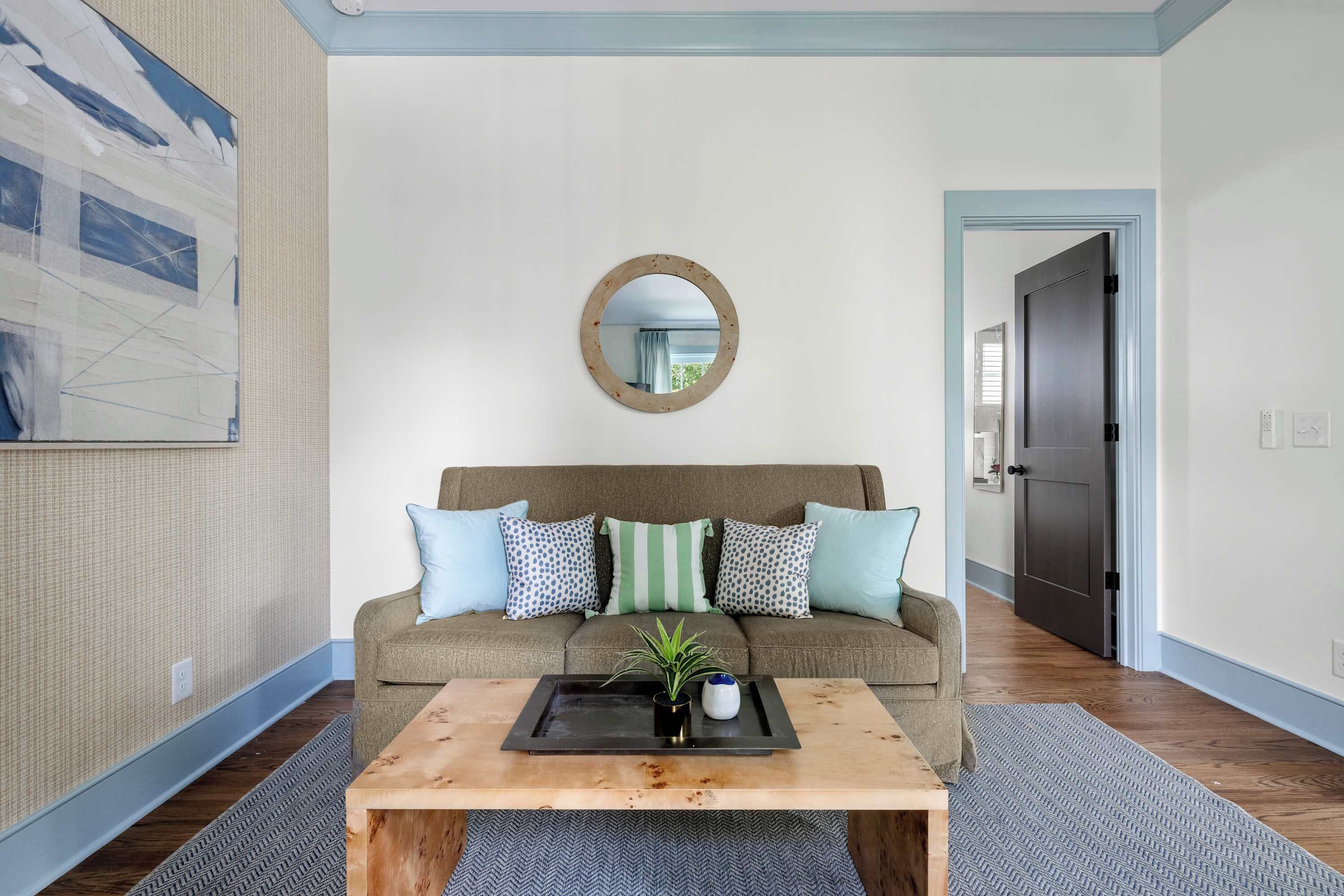 A living room with a sofa, a coffee table, a mirror, and a door in the background.