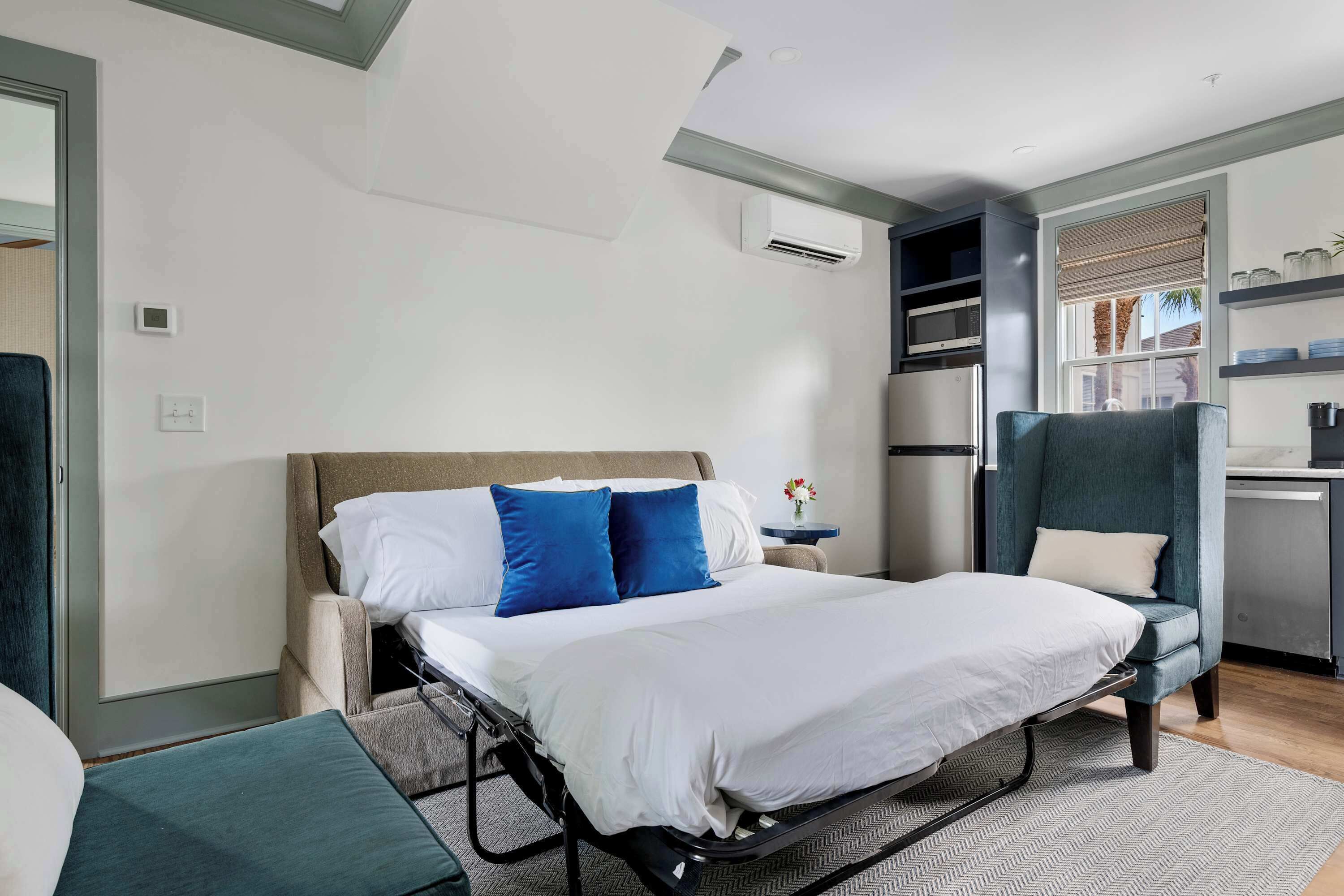 Een moderne hotelkamer met een bed, een bureau en een stoel. Er is een raam met uitzicht op het exterieur.
