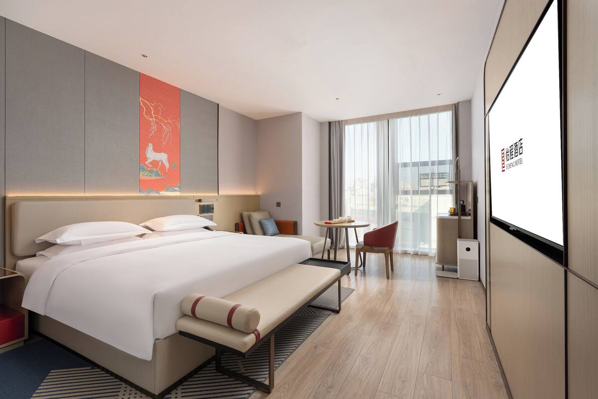 Een moderne hotelkamer met een groot bed, nachtkastjes, een bureau en een stoel.
