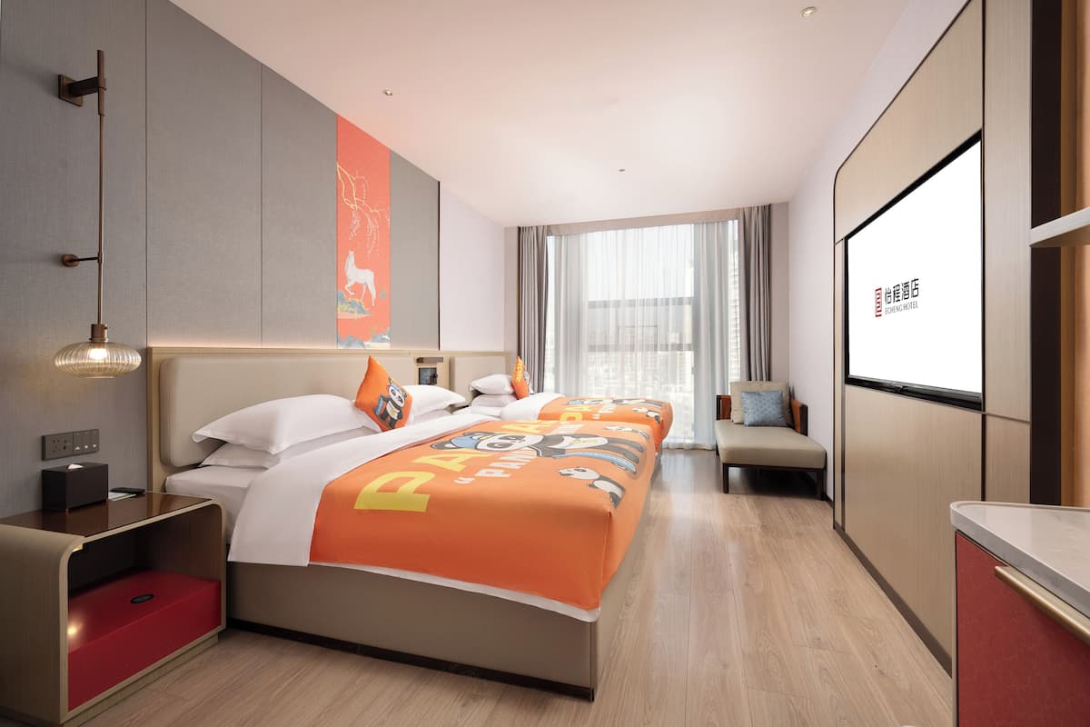 Een hotelkamer met een bed, nachtkastjes, een bureau en een groot raam.