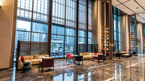 A spacious lobby with a high ceiling, large windows, a seating area with sofas and chairs, and a long bookshelf. - Nanning Huafengcheng ECHENG Hotel (Nanning)