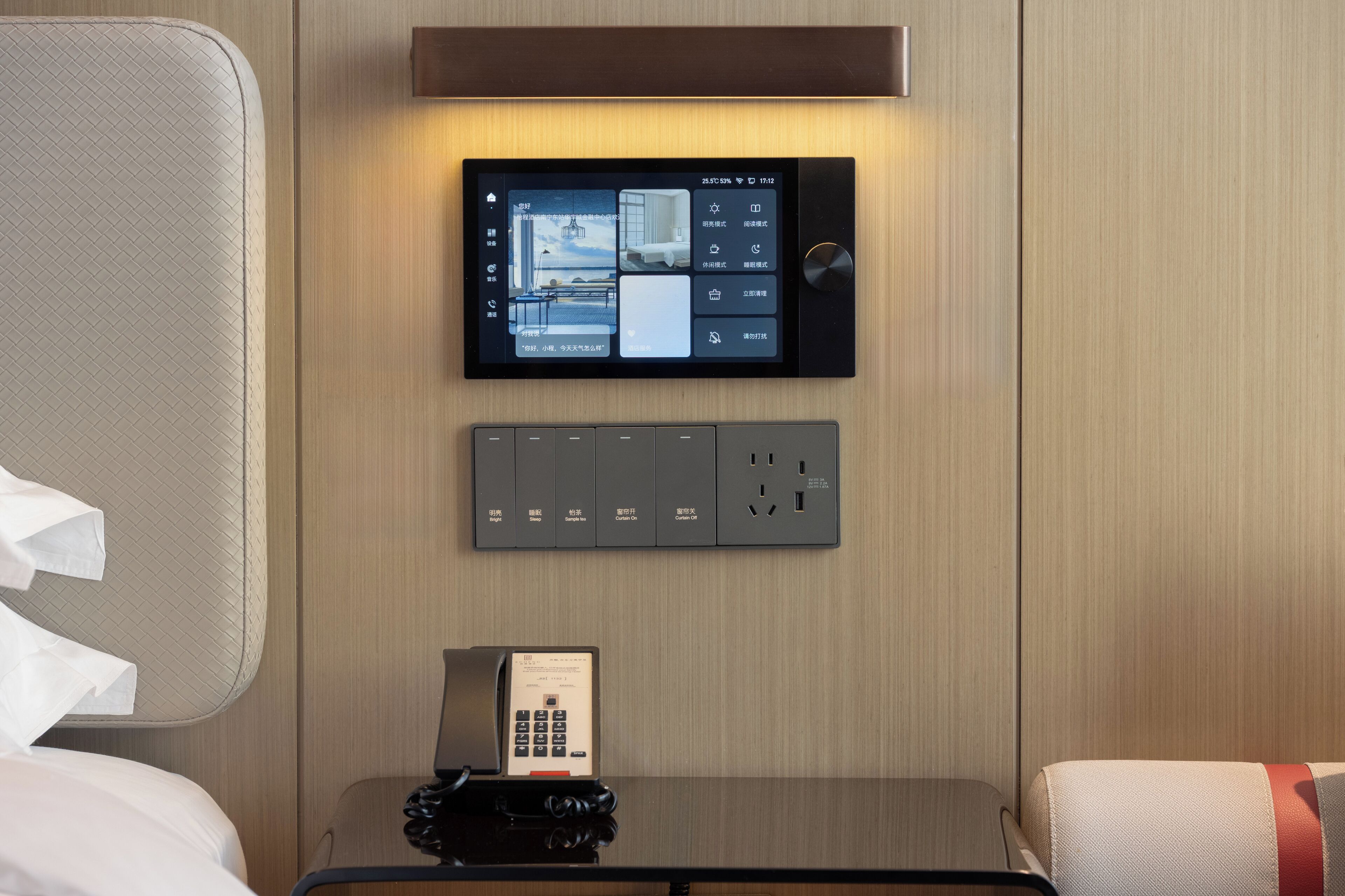 Panel de control con pantalla digital y teclado, probablemente para acceso o control de la habitación, fijado a la pared en una habitación de hotel.