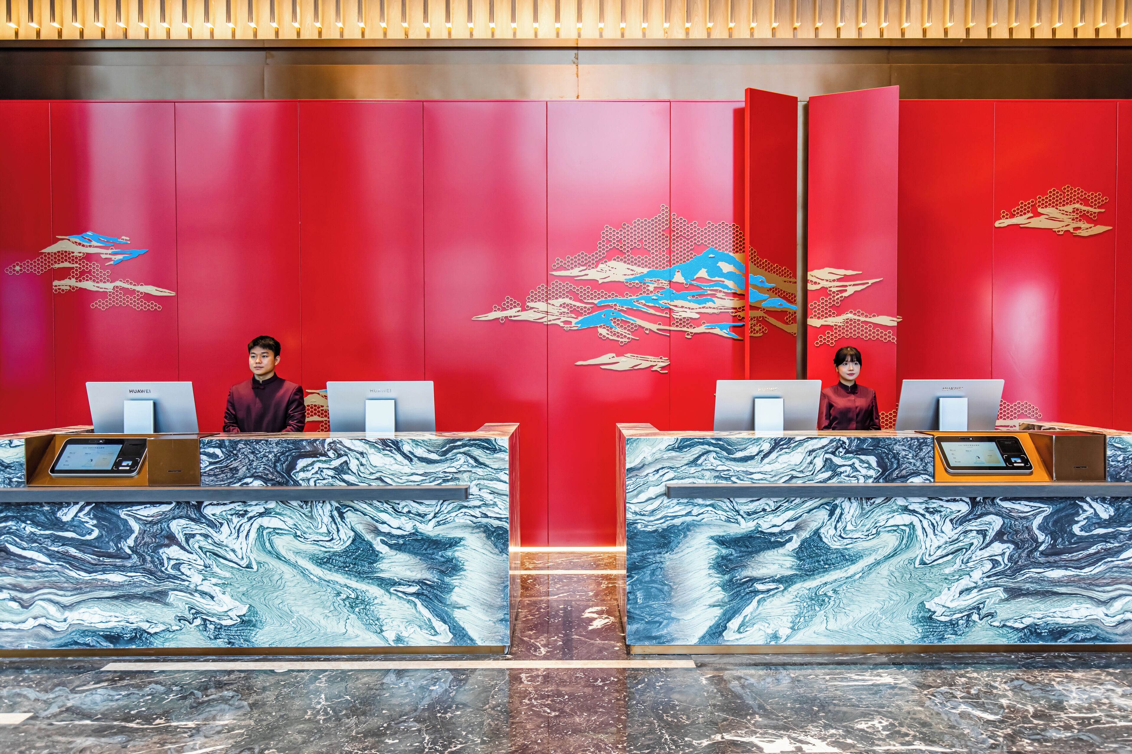A hotel reception area with red walls and marble counters.