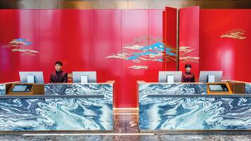 A hotel reception area with red walls and marble counters.