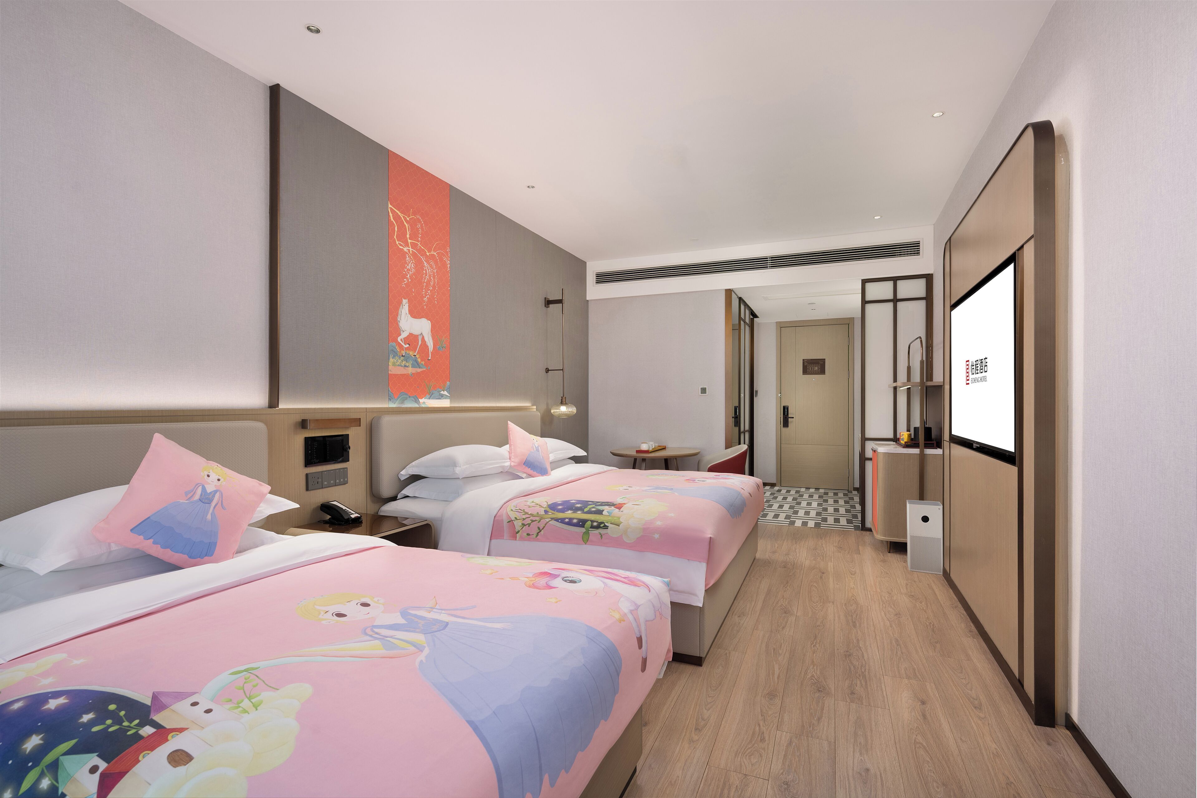 A hotel room with two beds, a small table, a desk, and a TV.