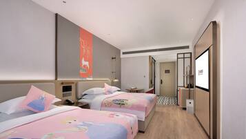 A hotel room with two beds, a small table, a desk, and a TV.