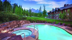 Une piscine bordée de pierres, des chaises longues et une vue sur les montagnes en arrière-plan.