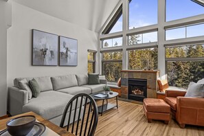 Ein modernes Wohnzimmer mit grauem Sofa, einem braunen Ledersessel, einem Holztisch und einem Kamin.