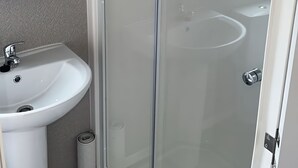 Un bagno con un lavandino bianco, una cabina doccia in vetro e un water.