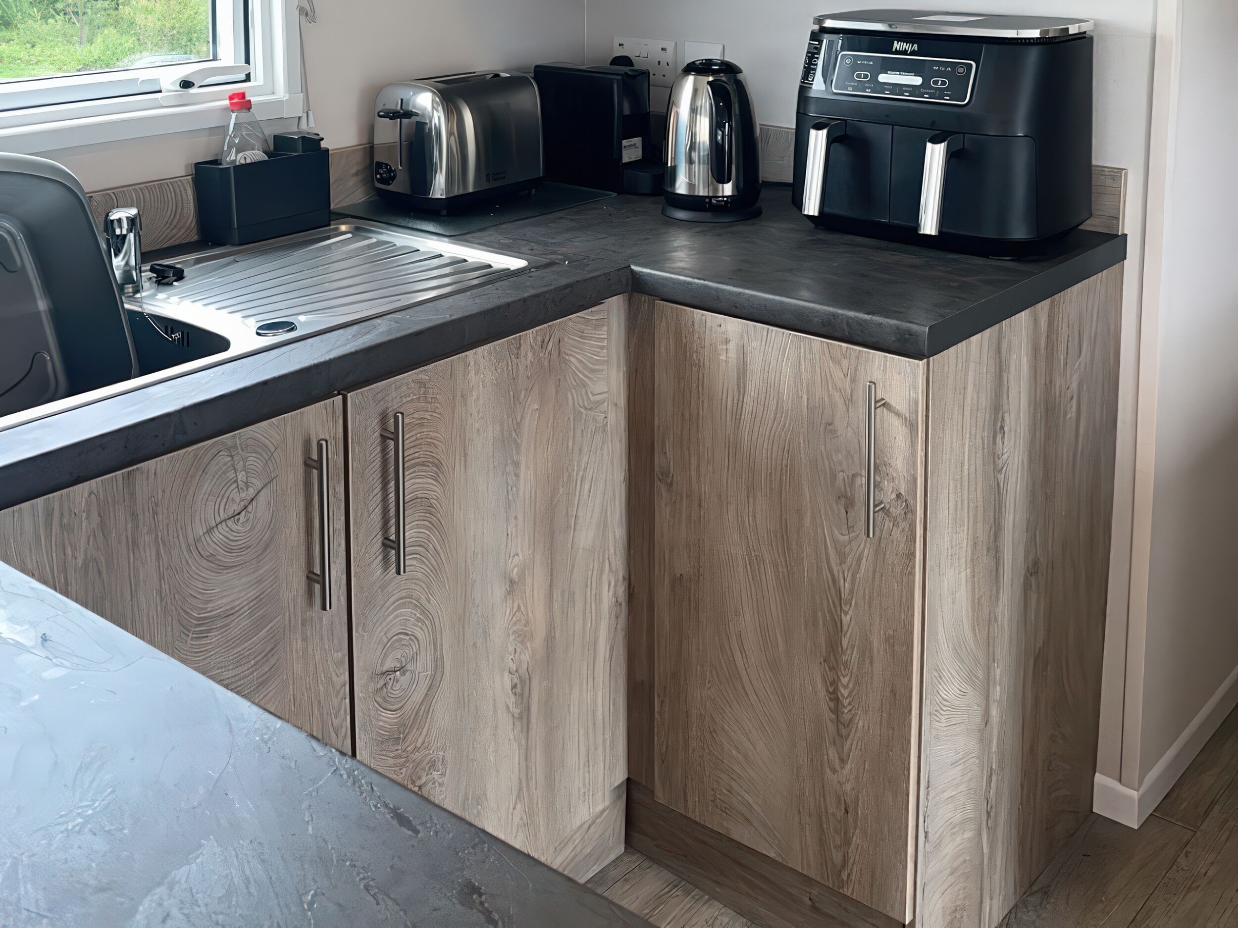 A modern kitchen with a built-in sink, a toaster, a kettle, and a coffee maker on the countertop.
