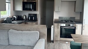 Una piccola cucina componibile con piano cottura a gas, forno e macchina per il caffè.