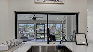 Eine moderne Küche mit großem Fenster, Spüle aus Edelstahl und Deckenventilator.
