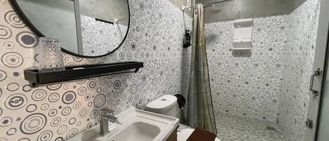 Ein Badezimmer mit Waschbecken, Spiegel, Toilette und Dusche.