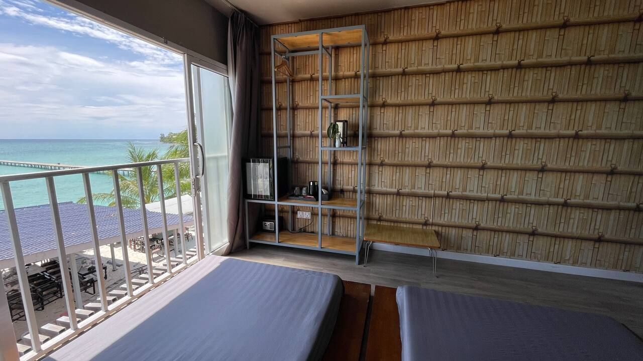 Un balcon avec vue sur l’océan, un mur en bambou et deux lits.