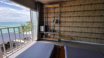 Un balcon avec vue sur l’océan, un mur en bambou et deux lits.