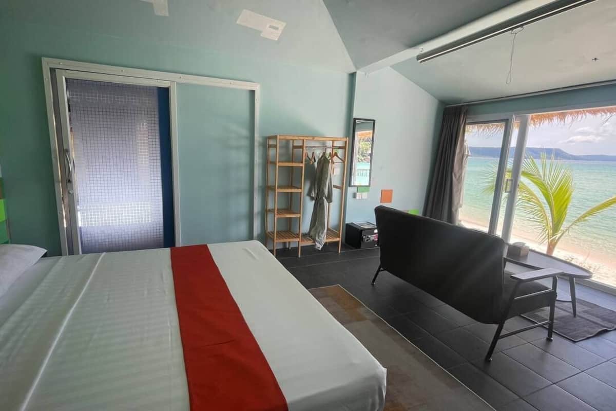 Una habitación de hotel con cama, zona de estar y vistas al mar, además de un armario.