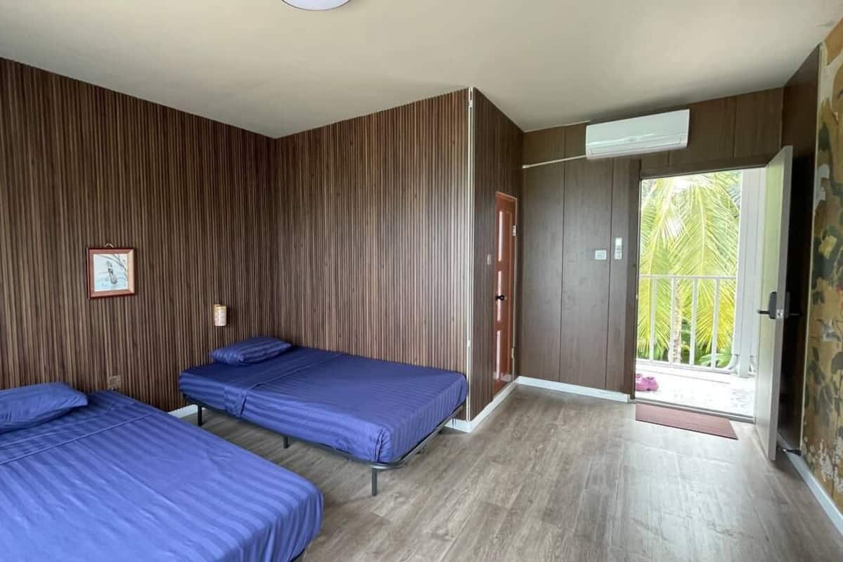 Una habitación con dos camas, paredes de madera, una puerta que da al exterior y una ventana pequeña.