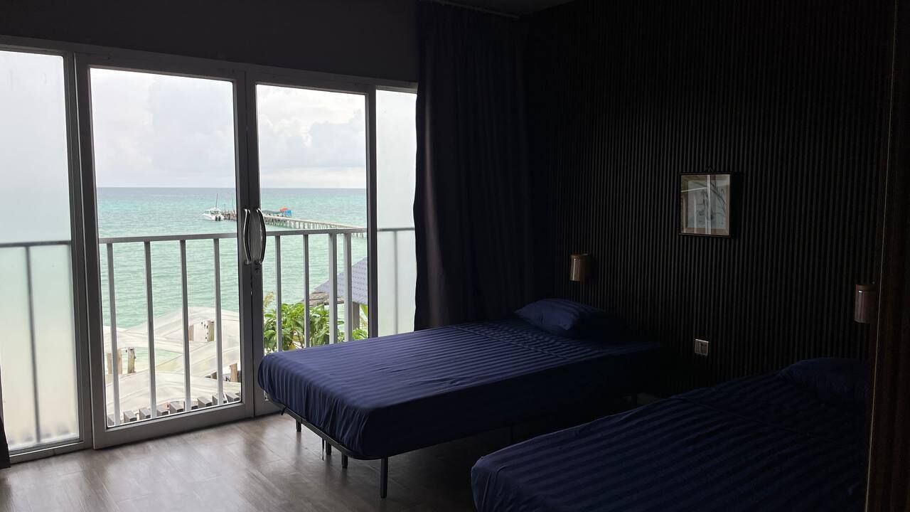 A room with two beds, a view of the sea, and a balcony.