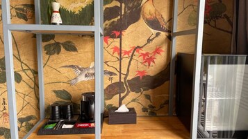 A room with tatami mats, a shoji screen, a traditional Japanese-style table with a teapot, cups, and a box of tissues.