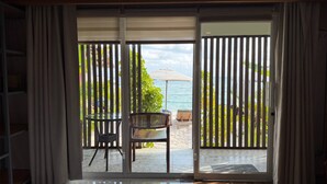 A sliding glass door leading to a patio with a table, chairs, and an umbrella. - White Sand Ark Resort (Koh Rong)